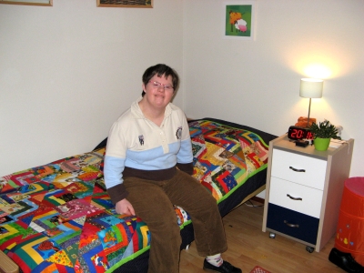 Foto van Annet op haar bed, met quilt.